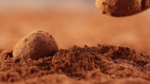 chocolate truffle is poured into cocoa powder with a spoon close - up slow motion