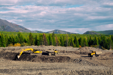 Excavator in the process of work in an industrial mountainous area (loads gold-bearing mountain soil into the body of a mining dump truck). Mining © Letopisec