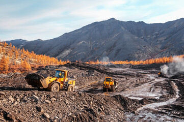 Wheel loaders and bulldozers in operation in an industrial mountainous area