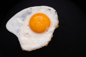 Fried egg on a black background. A popular breakfast is scrambled eggs. The photo