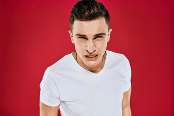 Fototapeta premium Emotional man white t-shirt displeased facial expression red isolated background cropped view