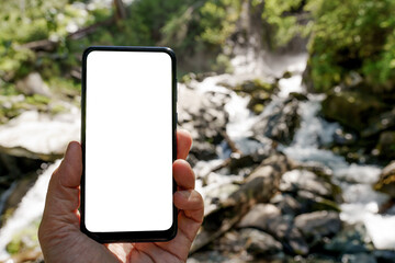 Fototapeta na wymiar smart phone in hand on the blur background of waterfall