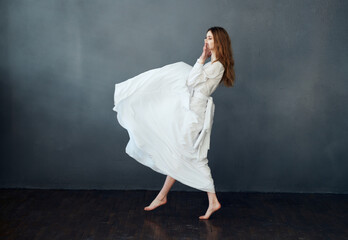 Charming lady in a white dress on a gray background dance gesticulating with her hands Copy Space...