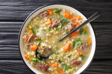 Tasty Scotch Rich broth filled with bite-sized pieces of root vegetable and tender lamb closeup in the plate on the table. Horizontal top view from above