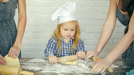 Kid baby in chef hat rolling dough. Child helping in kitchen. Homemade cooking and baking.