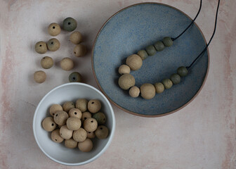 Handmade clay beads and necklace. Ceramic handcrafted items and stoneware plates. Top view.