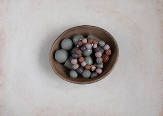 Handmade clay beads and bracelets in a stoneware decorative plate. Ceramic handcrafted items. Top view.