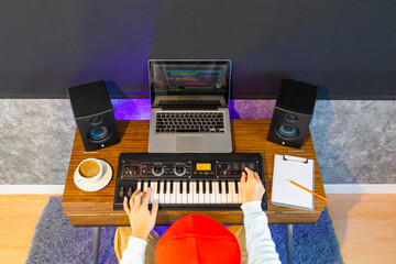 top view of male musician, composer, songwriter arranging music on keyboard synthesizer and computer on desk in home studio. music production technology concept - obrazy, fototapety, plakaty