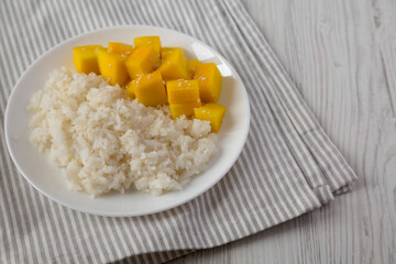 Homemade Sticky Rice with Mango and Sesame Seeds on a white plate , side view. Copy space.