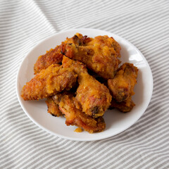 Homemade Spicy Mango Chicken Wings on a white plate on cloth, low angle view.