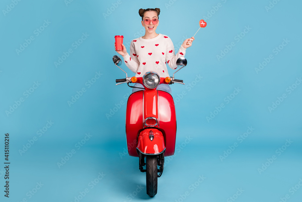 Poster photo of lady drive moped hold cup candy stick wear glasses heart print white pullover isolated blue