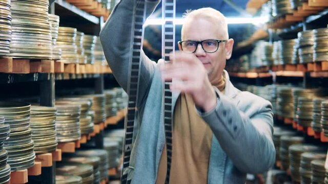 Male employee is looking closely at the old film tape