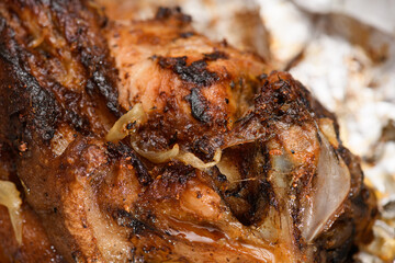 baked meat and fried onions on a baking sheet, pork ham on foil and wooden background, home cooking