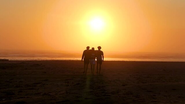 Three best friends savoring a moment together as they walk towards sunset over the vast horizon.