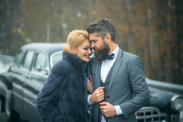 Young beautiful couple relaxing together walking at a retro car. Vintage people.