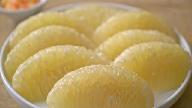 Fresh peeled pomelo, grapefruit or shaddock on white plate