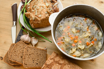 baked meat, soup and blood sausage on a plate, green onion and garlic on wooden background, home...