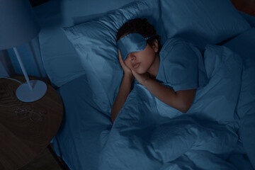 people, relax and comfort concept - young african american woman in eye mask sleeping in bed at...