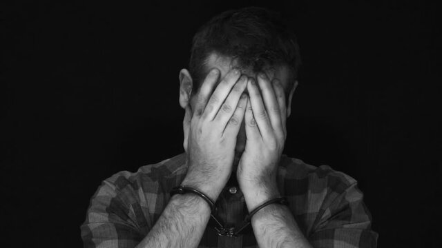a man in handcuffs is crying. the criminal repents and cries. arrest of a criminal