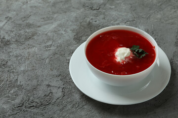 Bowl of tasty borscht on gray background