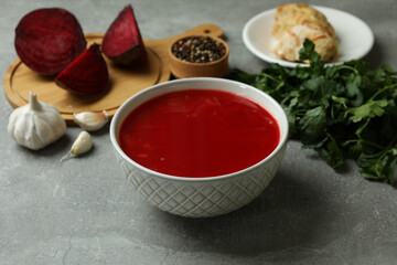Concept of tasty eating with borscht and ingredients on gray table
