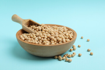 Wooden bowl with scoop and chickpea on blue background