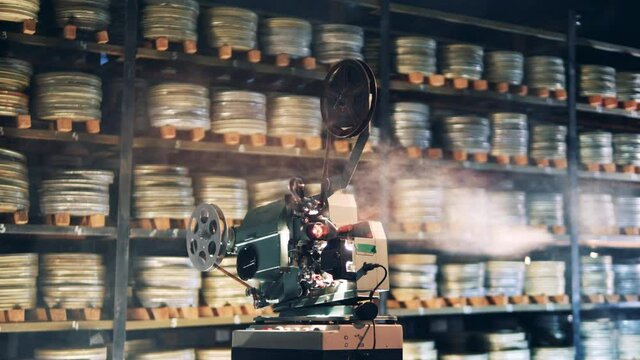 Film archive with a projector working in smoke. Retro film, vintage technology concept.
