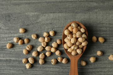 Spoon with fresh chickpea on gray textured background