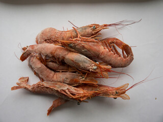 Deep frozen big rose lobsters with long antennas and slender legs top view on white surface