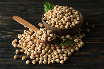 Bowl and spoon with chickpea on wooden table