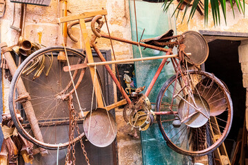 Italy, Apulia, Province of Lecce, Lecce. Old rusty bicycle and other odds and ends for sale.