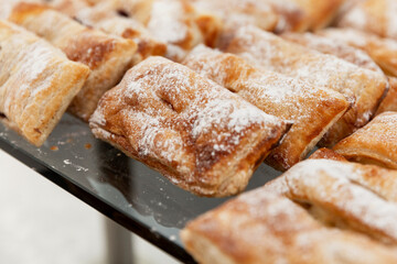 Rows of mouth-watering pastries on a tray on the table. Catering for business meetings, events and celebrations. Close-up.