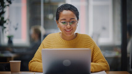 Portrait of Young Latin Marketing Specialist in Glasses Working on Laptop Computer in Busy Creative...