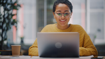Portrait of Young Latin Marketing Specialist in Glasses Working on Laptop Computer in Busy Creative...