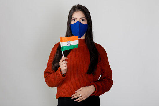 Portrait of a young beautiful female holding the Indian flag, tricolour on display by pretty woman to show national pride.