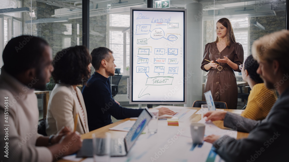 Poster Project Manager Makes a Presentation for a Young Diverse Creative Team in Meeting Room in an Agency. Colleagues Sit Behind Conference Table and Discuss Business Development, User Interface and Design.