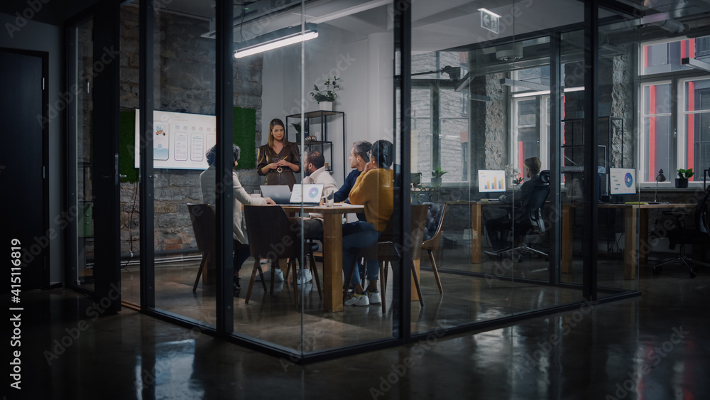 Poster project manager makes a presentation for a young diverse creative team in meeting room in an agency.