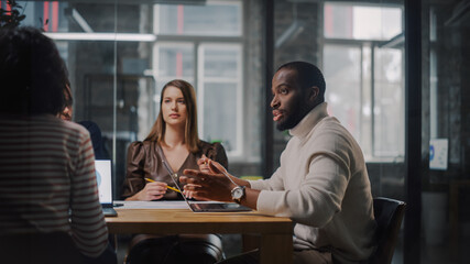 Young Creative Team Meeting with Business Partners in Conference Room Behind Glass Walls in Agency....