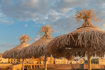 Italy, Apulia, Province of Lecce, Gallipoli. Wicker umbrellas on the beach.