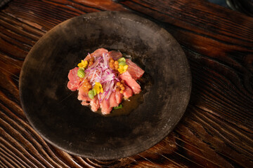 sashimi de atun con edamames en plato rustico negro 