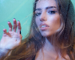 Fashion and beauty. Sexy model with beautiful long hair on water drop blue background.