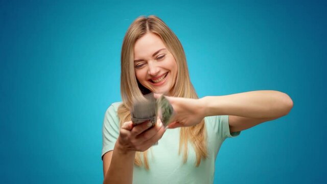 Young woman showing gesture of wasting money against blue background, materialist, shopping concept