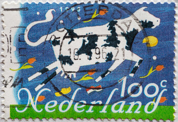NETHERLANDS - CIRCA 1995: a postage stamp printed in the Netherlands showing the painting of a black and white spotted cow, wooden shoes, cheese and tulips
