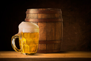 Beer. Still life with Vintage beer barrel and glass light beer. Fresh amber beer concept. Green hop and gold barley on wooden table. Ingredients for brewery. Brewing traditions