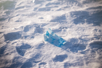 a blue medical mask lies alone on the snow in the rays of the sunset.  thrown out medical mask.  winter season and colds.  illness and cold.  medical mask under the snow.