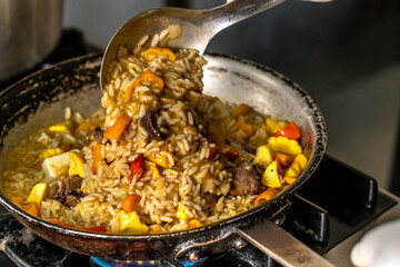 preparacion de arroz cremoso estilo risoto con cola de res y vegetales en sarten de metal 