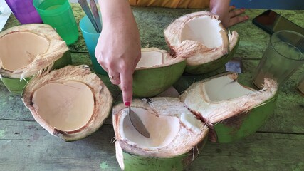 Close up of woman hand opening fruit of green coconut
