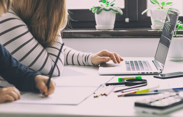 The kid is drawing while his mom working with laptop