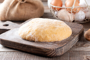 Fototapeta na wymiar Raw dough on a cutting board on a rustic wooden table. Frozen dough