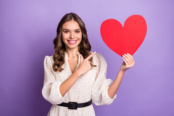 Photo portrait of woman pointing finger red postcard on valentines day smiling isolated on pastel purple color background